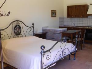 a bedroom with a white bed and a kitchen at Etna Wine Azienda Agrituristica in Passopisciaro