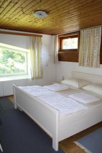 een groot wit bed in een kamer met 2 ramen bij Ferienwohnungen Benedikt in Villach