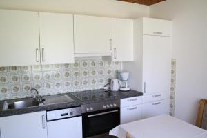 a kitchen with white cabinets and a sink at Ferienwohnungen Benedikt in Villach