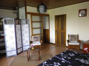 a living room with two chairs and a bed at Chambre d'hôtes La Haie Fleurie in Chevillard