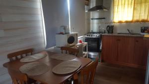 eine Küche mit einem Tisch mit Stühlen und einem Herd in der Unterkunft Cabaña I Punta Negra in Piriápolis + 14 Fotos