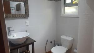 a white bathroom with a toilet and a sink at Cabaña I Punta Negra in Piriápolis
