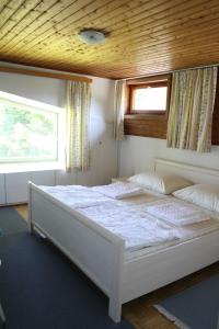 1 dormitorio con 1 cama blanca grande y techo de madera en Ferienwohnungen Benedikt en Villach