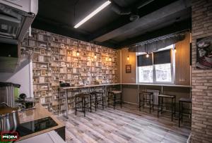 a bar with stools in a room with a brick wall at Nora Hostel in Yuzhno-Sakhalinsk