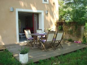 una terraza de madera con mesa y sillas. en Gîte au Martin Pêcheur, en Laiz