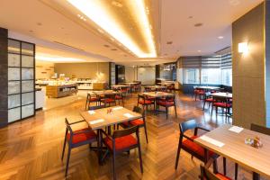 a restaurant with tables and chairs and a kitchen at Meitetsu Toyota Hotel in Toyota