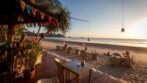 a beach with tables and chairs on the sand at Bamboo Bungalows in Ko Phayam