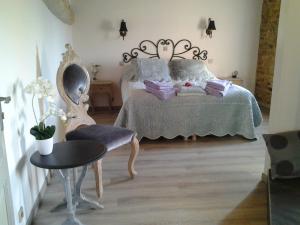 a bedroom with a bed and a chair and a table at Le Clos du Merle in Savigny