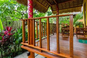 a wooden porch of a resort with a table and chairs at Rama Homestay in Nusa Penida