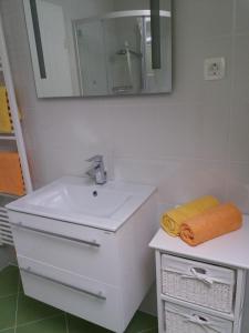 La salle de bains blanche est pourvue d'un lavabo et d'un miroir. dans l'établissement Apartma Momo, à Bohinj
