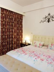 a bedroom with a large white bed with flowers on it at Jhen Pin Xuan B&B in Taitung City
