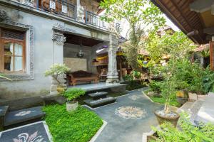a courtyard of a house with a bench and trees at Bali Moon Guest House in Ubud