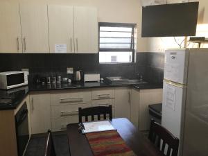 a kitchen with a stove, refrigerator, sink and microwave at A Little Guesthouse in Bloemfontein