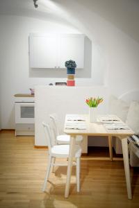 a white kitchen with a table and white chairs at City Center Apartment in Vienna