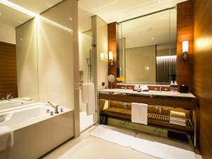 a bathroom with a sink, mirror and bath tub at Eslite Hotel in Taipei