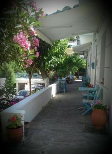 un bâtiment avec des tables et des chaises, des arbres et des fleurs dans l'établissement Smaragdi Studios and Rooms, à Agios Kirykos