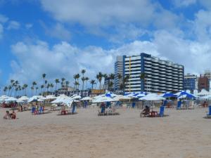 una playa con sombrillas azules y blancas y un edificio en Bahia Suites Residence, en Salvador