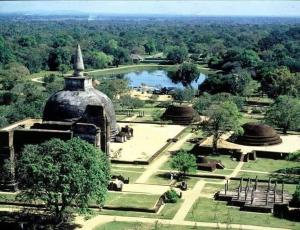 a view of a park with a lake and a building at Canal Side Guest House Polonnaruwa in Polonnaruwa