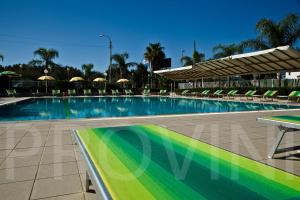 une grande piscine avec des chaises et des parasols dans l'établissement Residence Atlante, à Leporano