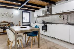 una cucina con armadi bianchi e tavolo e sedie in legno di Ponte Milvio Luxury House a Roma