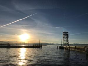 フリードリヒスハーフェンにあるApartment Friedrichshafen Centerの桟橋付きの水上夕日