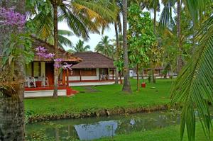 a resort with a pond in front of a house at Coconut Lagoon Kumarakom- CGH Earth in Kumarakom