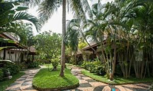 a resort yard with palm trees and a walkway at Salad Beach Resort - SHA Extra Plus in Salad Beach