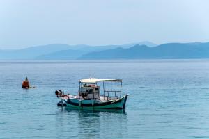 a small boat in the middle of a large body of water at SUN HOTEL KINETA Beach Front in Kineta