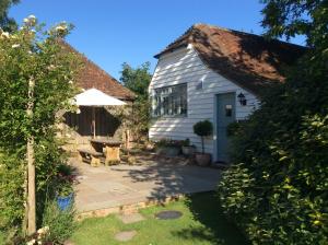 a cottage with a patio and an umbrella at Freshwater Barn in Benenden