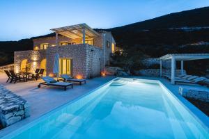 a villa with a swimming pool in front of a house at Urania Luxury Villas in Vasiliki