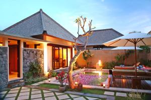 a woman sitting in front of a house with a pool at The Sanyas Suite Bali in Seminyak