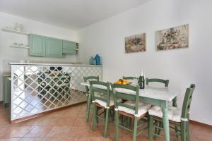 a dining room with a table with green chairs at Soleado beach house in Pietrasanta