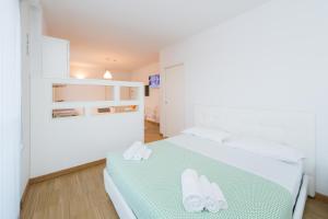 ミラノにあるハウジング32 アパートメンツの白いベッドルーム(緑の毛布付きのベッド付)