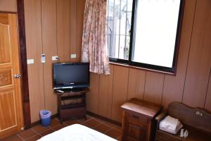 um quarto com uma televisão, uma cama e uma janela em Shi-Jia B&B em Jiufen