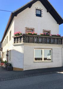 a white house with a balcony with flowers on it at Gästehaus Doll in Herresbach