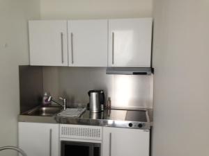 eine Küche mit weißen Schränken und einem Waschbecken in der Unterkunft Au Calme in Sint-Genesius-Rode