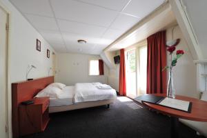 1 dormitorio con cama, escritorio y ventana en 't Streefkerkse Huis, en Zoutelande