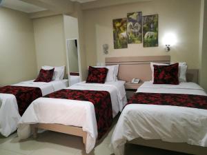 Habitación de hotel con 3 camas con almohadas rojas en Hotel Spa Machupicchu, en Tacna