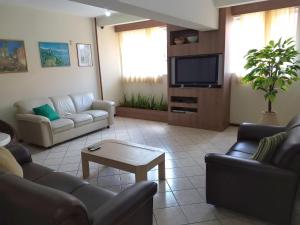 Una sala de estar con sofás y un televisor de pantalla plana. en Ilhamar Canas Hotel, en Florianópolis