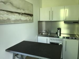 a kitchen with white cabinets and a black counter top at Au Calme in Sint-Genesius-Rode