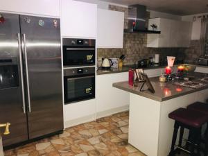 a kitchen with a stainless steel refrigerator and white cabinets at Modern cosy room with private bathroom in Harrow
