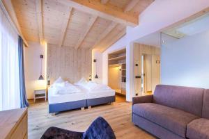 a large bedroom with a bed and a couch at Hotel Garni Broi - Charme & Relax in Selva di Val Gardena +75 photos