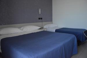 two beds in a hotel room with blue sheets at Hotel Piccolo Paradiso in Bordighera