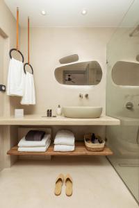a bathroom with a sink and a shelf with towels and shoes at Chora Kythnos Suites adults only in Kithnos