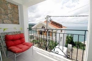una silla roja sentada en un balcón con vistas en Apartmani Kasija, en Dobra Voda