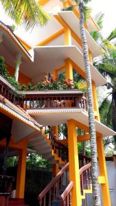un bâtiment jaune avec des escaliers et un palmier dans l'établissement Thriphala Ayurveda Yogashram, à Trivandrum