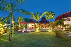 an exterior view of a house with palm trees at Villa Nico in Canggu