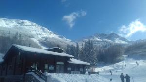 domek narciarski na pokrytej śniegiem górze z ludźmi w obiekcie Appartamento La Volpe w mieście Pian degli Ontani