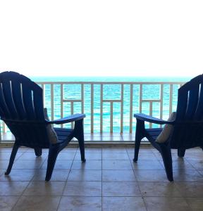 2 sillas sentadas en un balcón con vistas al océano en Sweet Serenity St Croix USVI, en Christiansted