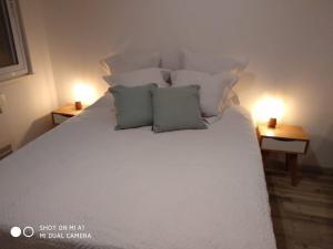 1 cama blanca con 2 almohadas y 2 lámparas en las mesas en Avenida Corrientes Studio - Obelisco en Buenos Aires